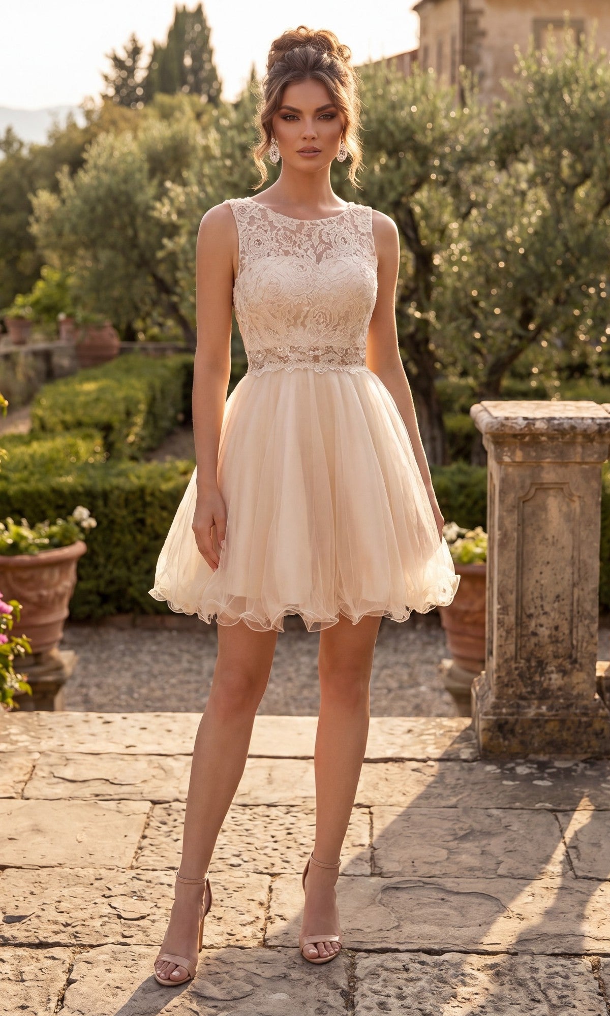 A woman stands outdoors wearing the Short Homecoming Dress: Chicas C1107 in Champagne Gold, a sleeveless knee-length dress with a lace bodice and tulle skirt, paired with nude heels. A stone walkway and lush greenery appear in the background.